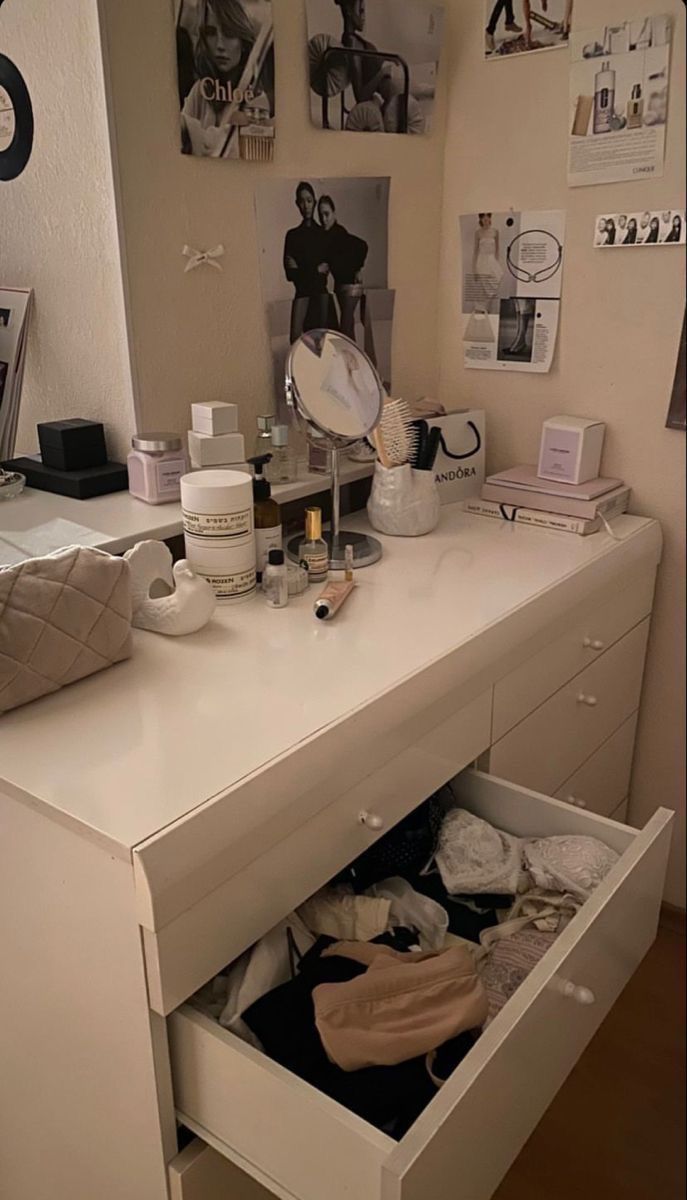 a white desk with drawers and pictures on the wall