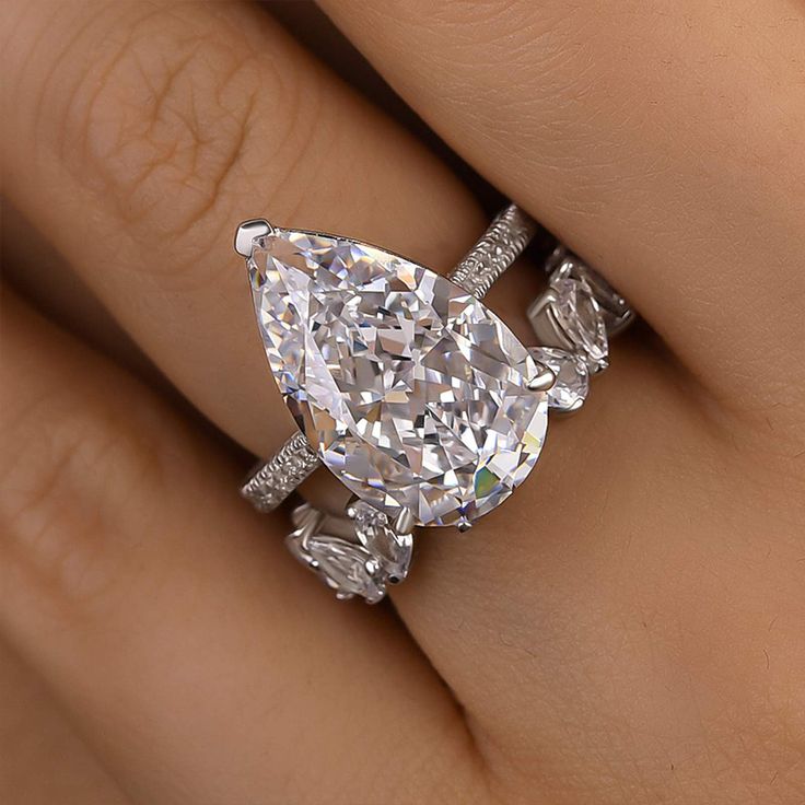 a woman's hand with a diamond ring on top of her finger and an oval shaped diamond in the middle