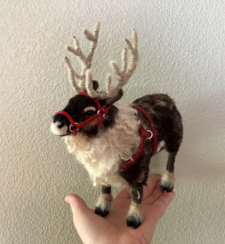 a hand holding a small toy reindeer with glasses on it's head and nose