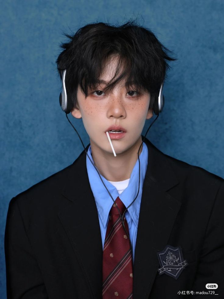 a young man wearing headphones and a suit