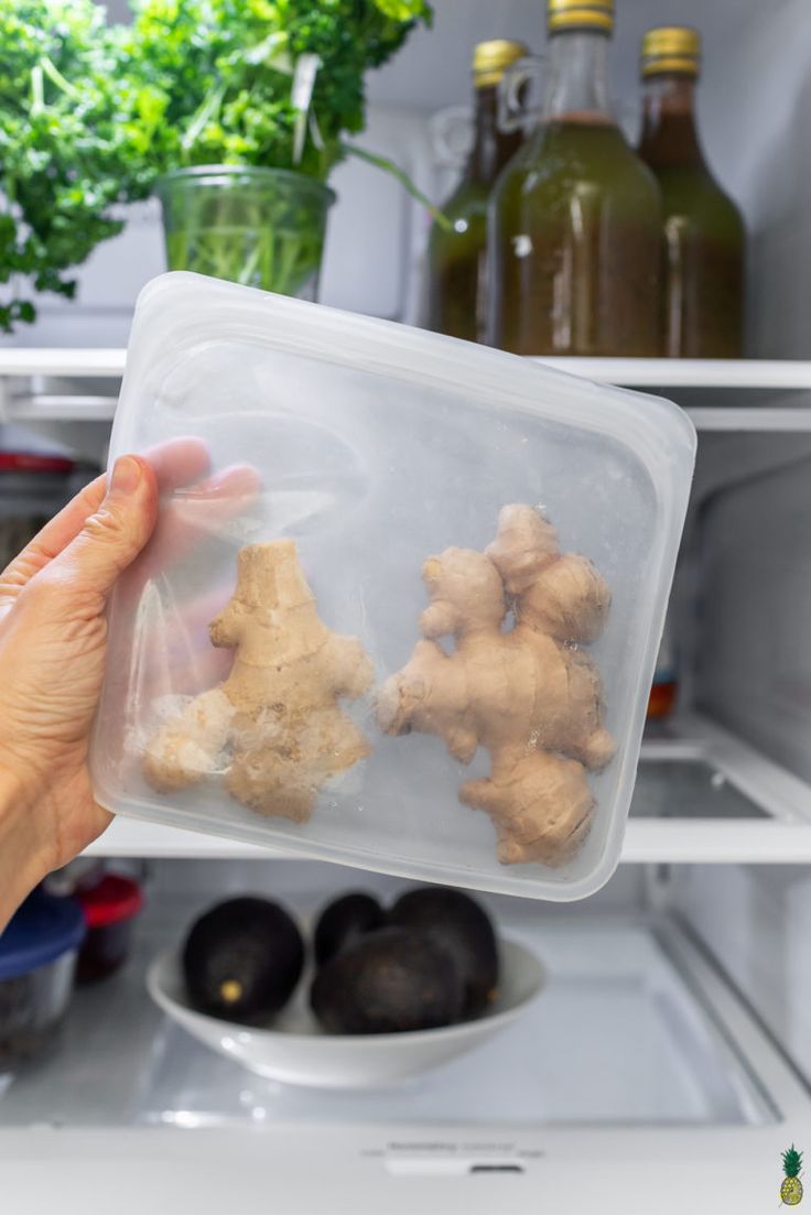 a person holding up some food in front of an open refrigerator