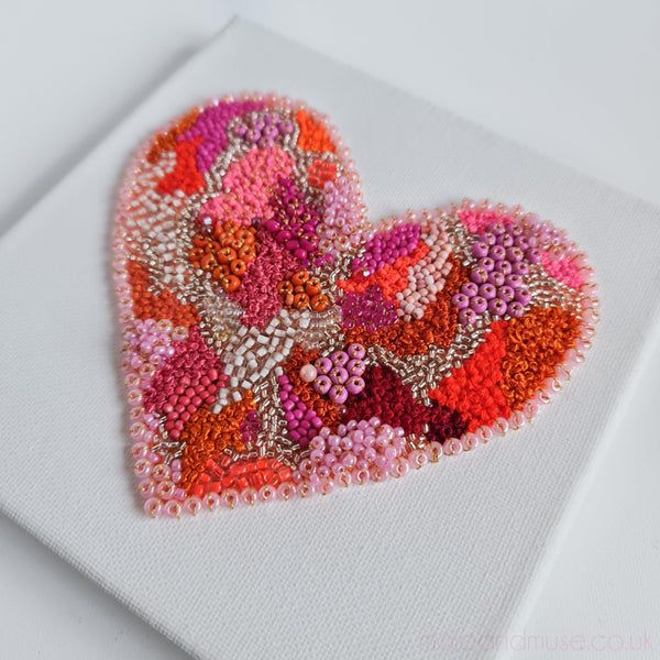 a close up of a heart on a piece of paper with bead work in the middle