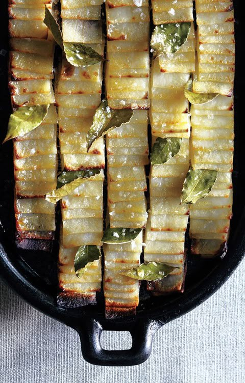 some food that is in a black pan on a white tablecloth and silverware