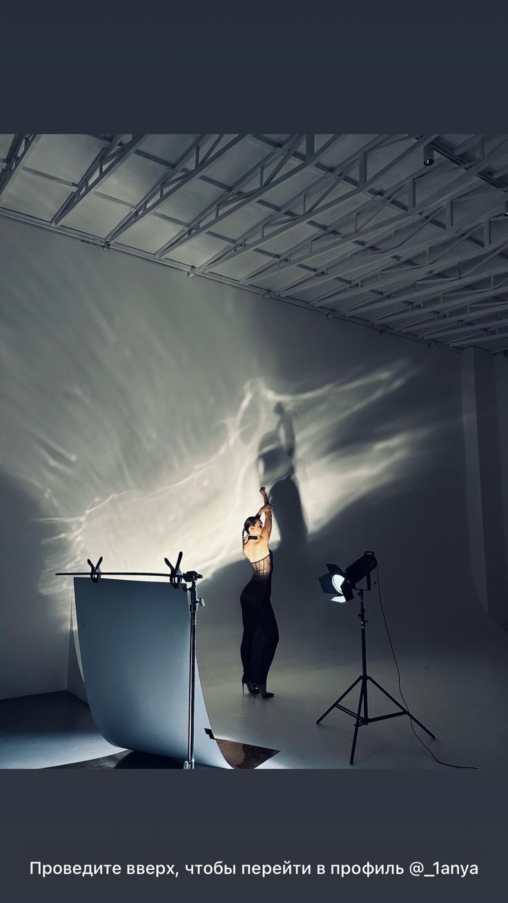 a woman is standing in front of a camera and light on the wall behind her