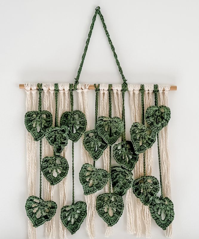 a green and white wall hanging with many hearts on it's sides, attached to a string