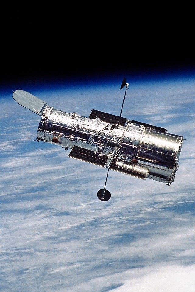 the space shuttle is flying in the air above the earth's surface, with clouds below