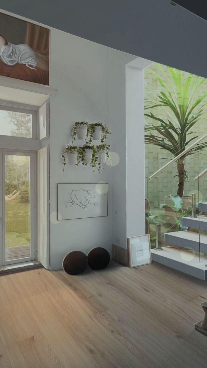 a living room filled with furniture next to a window covered in plants and potted plants