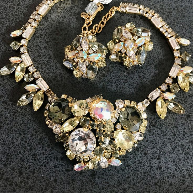 "A spectacular Vintage HOBE faceted, quality, sparkling, necklace and matching clip earrings.  Condition is great-gold plating and stones are excellent.  The working clip earrings are signed Hobe.  earrings 1 1/3\", the necklace is approx 18\" in length counting chain extension at back of chain.   It can be worn any shorter length than 18\".  THE center is approx 3\" by 2\".  The overall color palate of the beautiful varied cut and colored glass jewels is gorgeous-clear crystal, grey, and other Vintage Gold Jewelry Sets For Party, Formal Jeweled Costume Jewelry Sets, Glamorous Gold Jewelry Sets For Evening, Formal Costume Jewelry Sets With Jewels, Evening Jewelry Sets With Sparkling Stones In Gold, Evening Gold Jewelry Sets With Sparkling Stones, Gold Jewelry Sets With Sparkling Stones For Evening, Vintage Gold Sparkling Jewelry, Vintage Sparkling Gold Jewelry