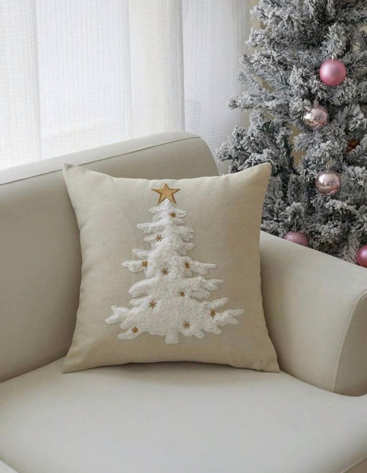 a white christmas tree pillow sitting on top of a couch next to a christmas tree