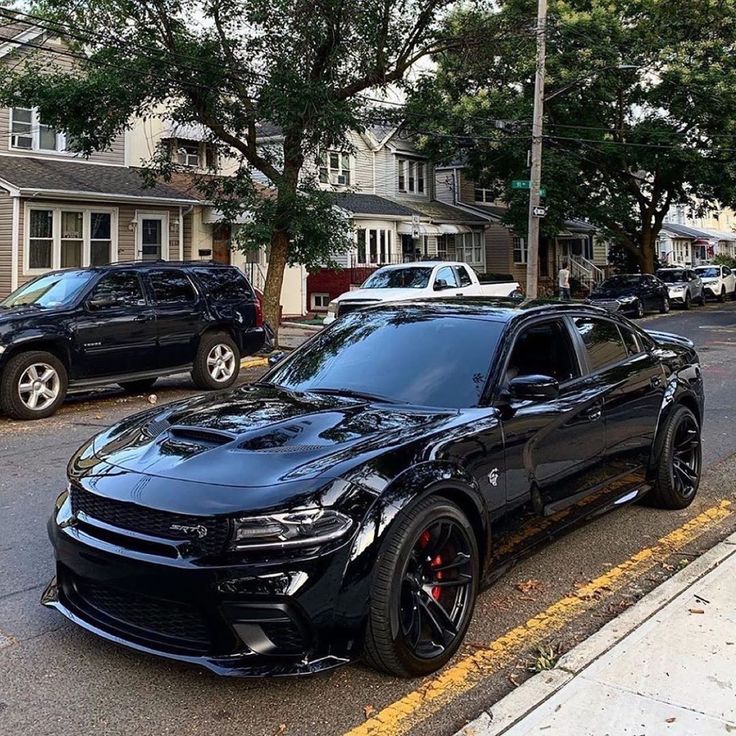 a black car is parked on the side of the road in front of some houses