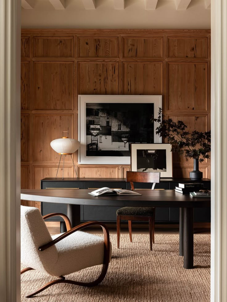 an office with wood paneling and chairs in the corner, along with a large desk