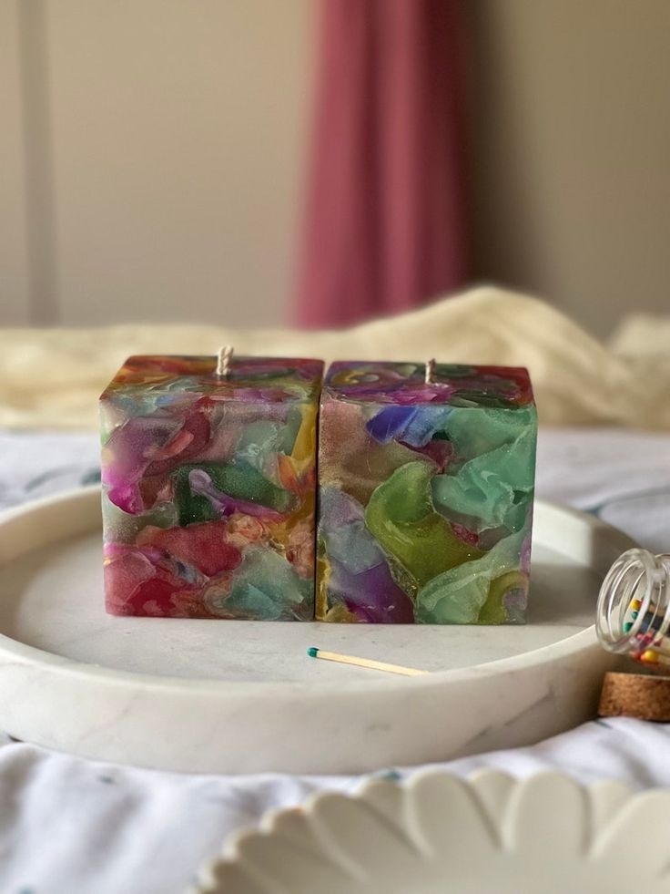 two square pieces of soap sitting on top of a white plate