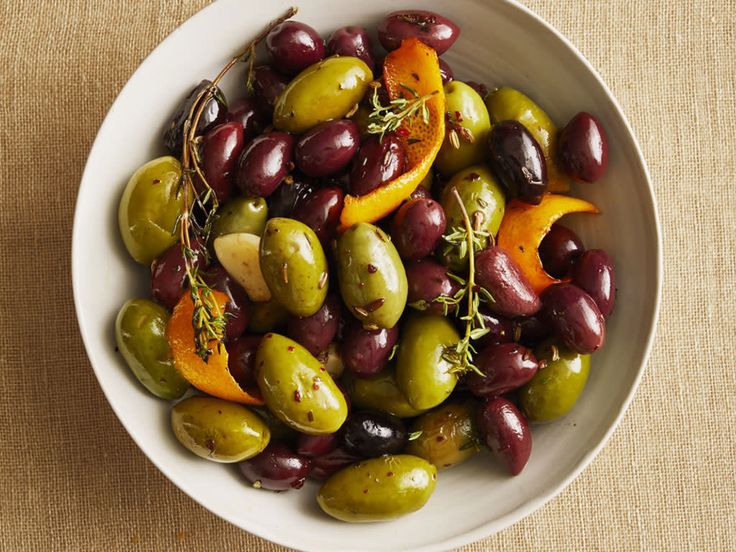 a white bowl filled with olives and orange slices