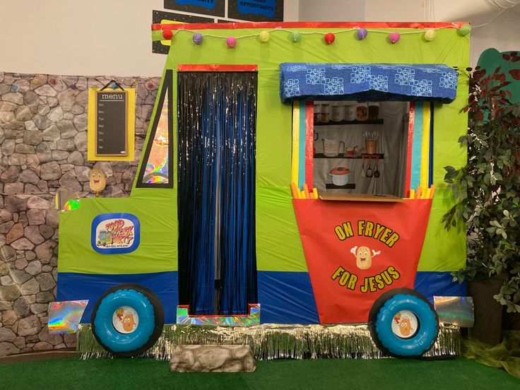 a brightly colored food truck decorated with streamers and decorations on display in a building