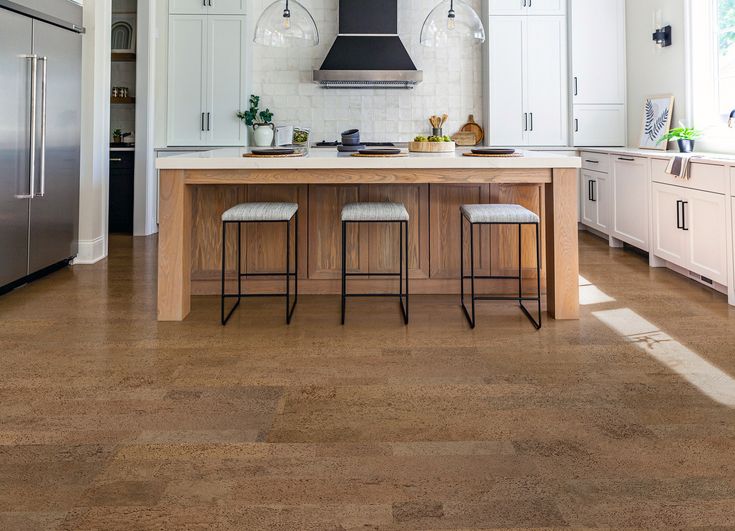 a kitchen with white cabinets and counter tops, two stools at the center island