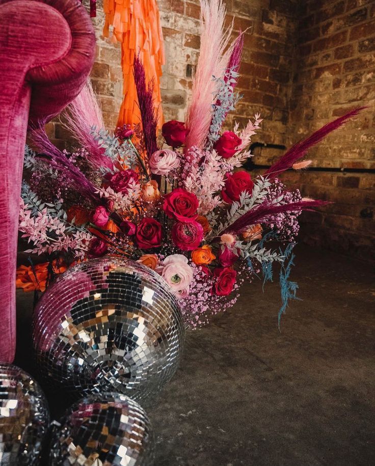 a vase filled with lots of flowers next to disco balls and mirrors on the floor