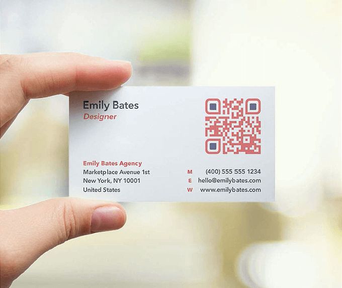 a person holding up a business card with qr code on it