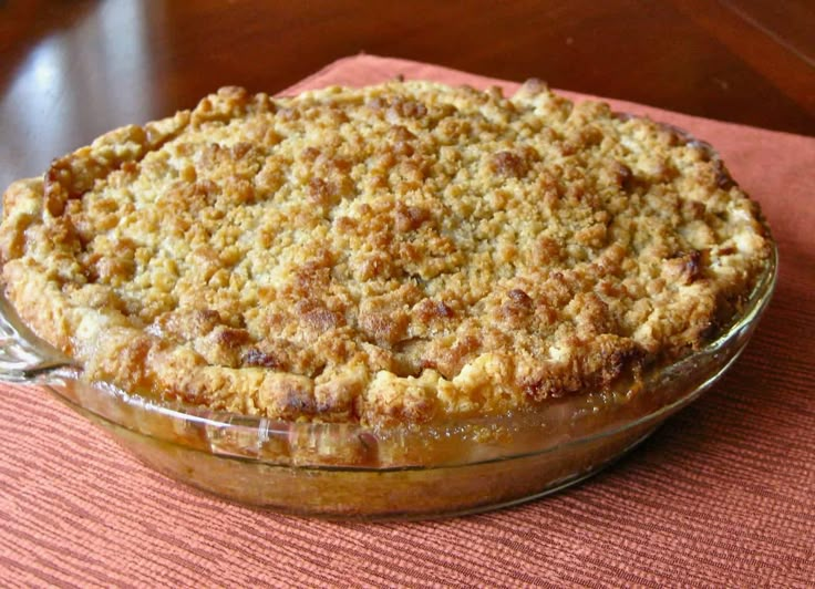 a pie sitting on top of a table next to a glass bowl filled with fruit