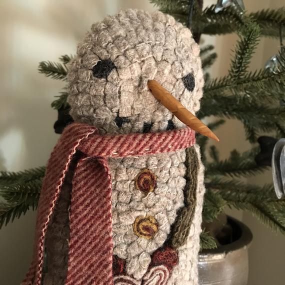 a crocheted snowman ornament sitting on top of a christmas tree