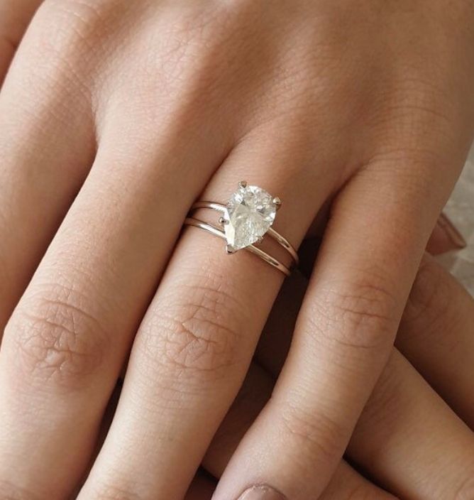 a woman's hand with a ring on her finger and an oval shaped diamond in the middle