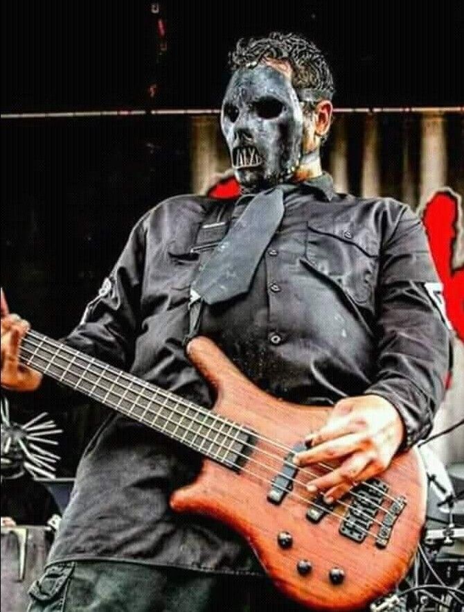 a man in black shirt playing a bass guitar with skull face paint on his face