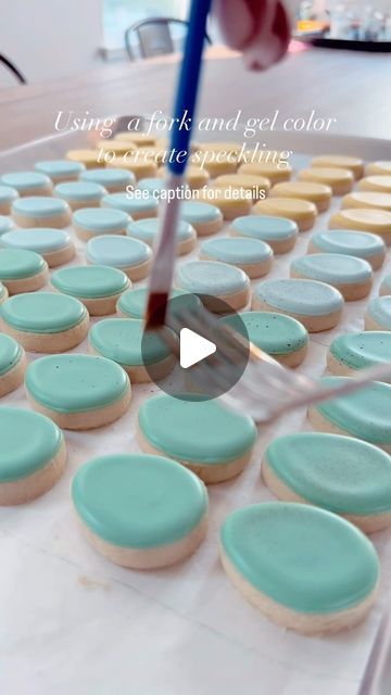 an image of some cookies being made with icing on a table and someone is using a blue brush to decorate them