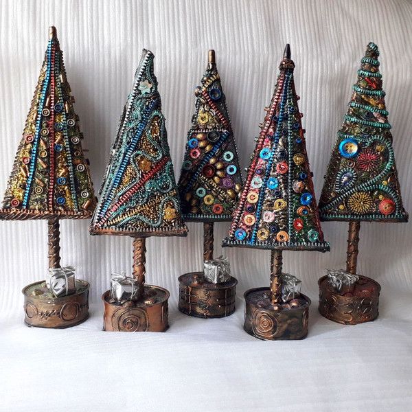 three small christmas trees made out of bead and wood, sitting on a white surface