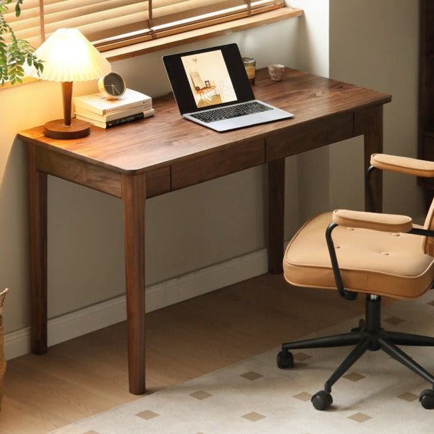 a laptop computer sitting on top of a wooden desk next to a lamp and chair