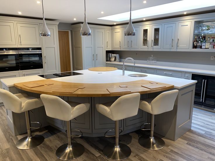 a large kitchen with an island in the middle and four chairs around it, as well as two pendant lights