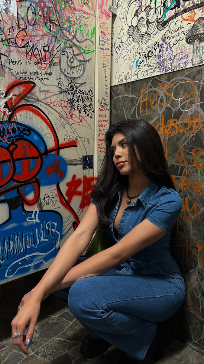 a woman sitting on the ground in front of graffiti covered walls