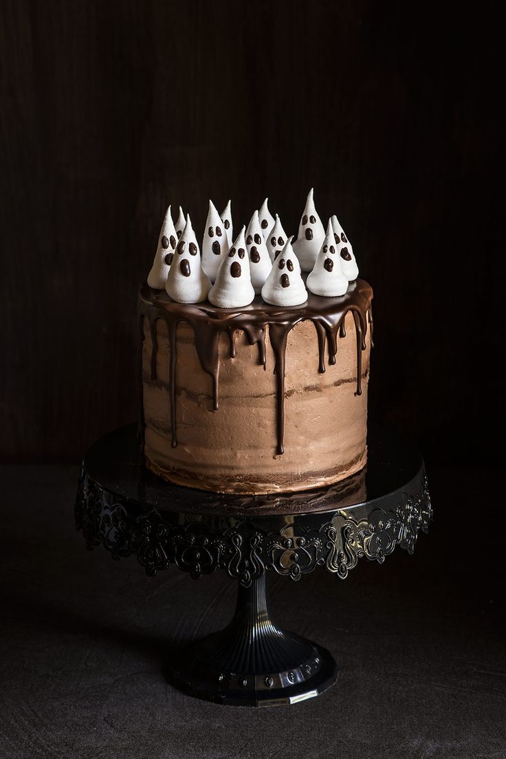 a chocolate cake with white frosting and spooky ghost heads on the top