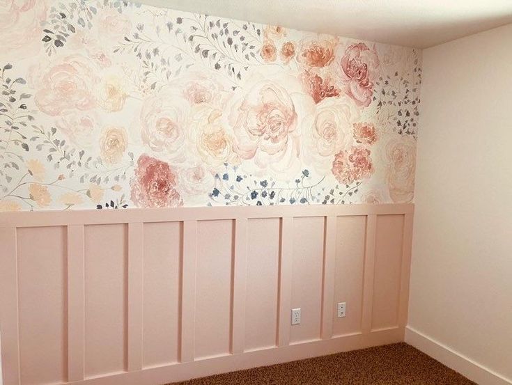 an empty room with flowers painted on the wall and wood paneling in the corner