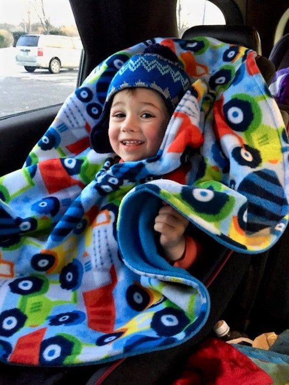 a little boy sitting in the back seat of a car with a blanket over his head