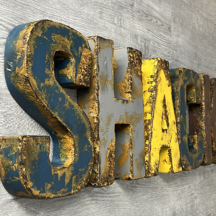 an old metal sign with the word shad painted yellow and blue on it's side