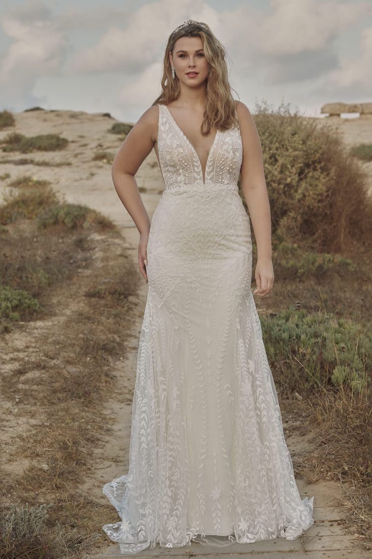 a woman in a wedding dress standing on a dirt road