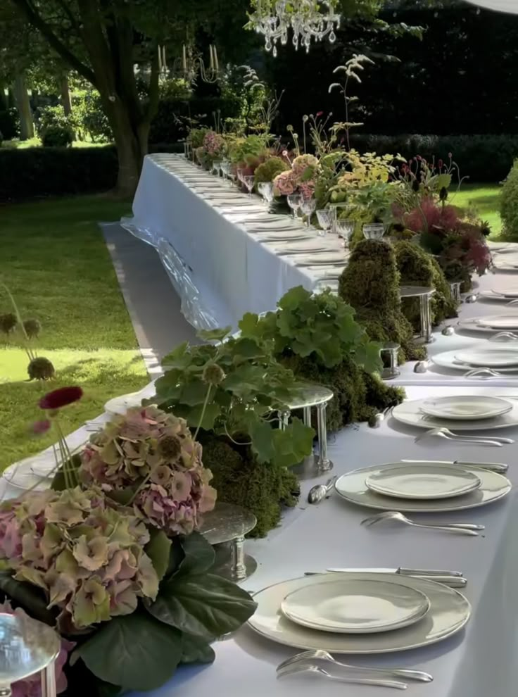 a long table is set with plates and silverware for an outdoor dinner or party