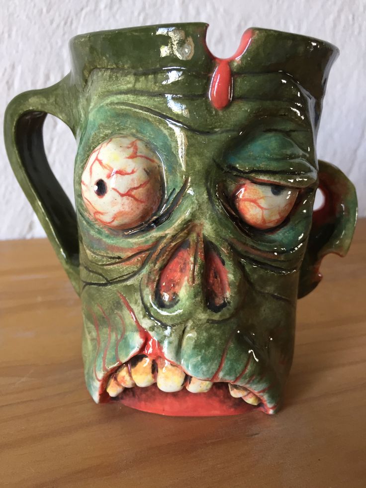 a ceramic mug with an evil face painted on it