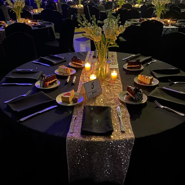 the table is set up with black linens and gold sequined runneres