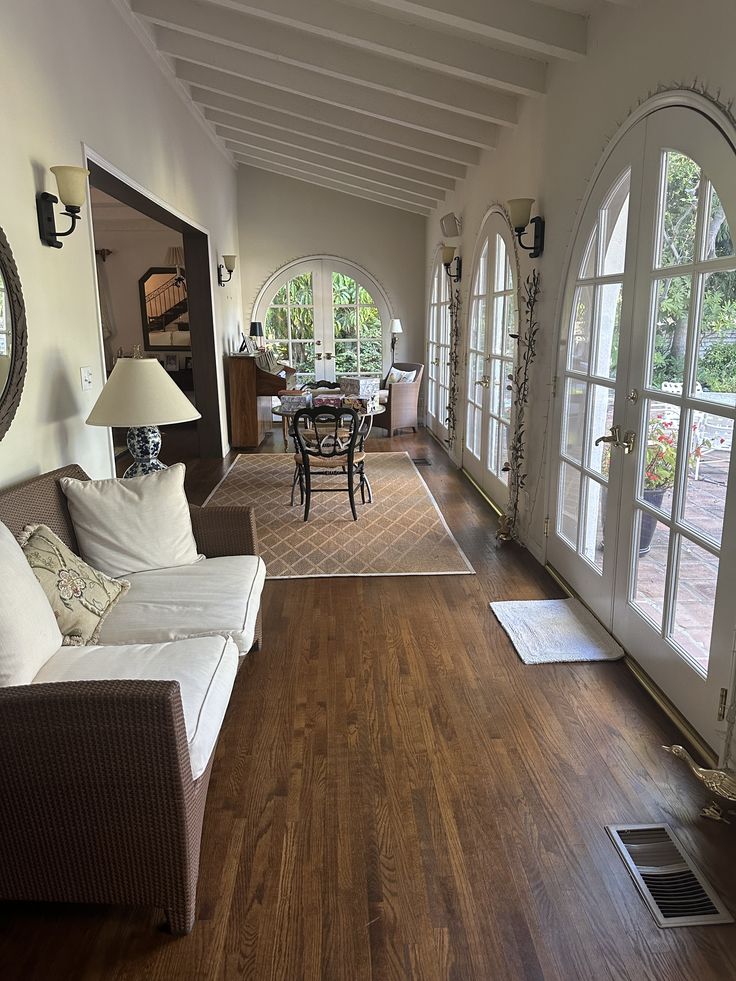 a living room filled with lots of furniture next to two large open doors and windows