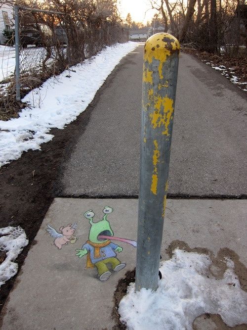 a street with snow on the ground and graffiti painted on the sidewalk next to it