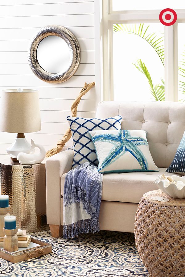 a living room filled with lots of pillows on top of a white couch next to a window