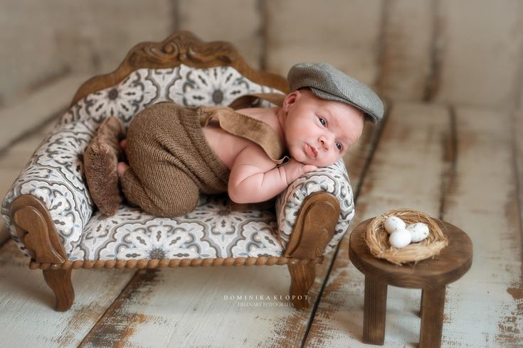 a baby laying in a chair next to a small bird nest