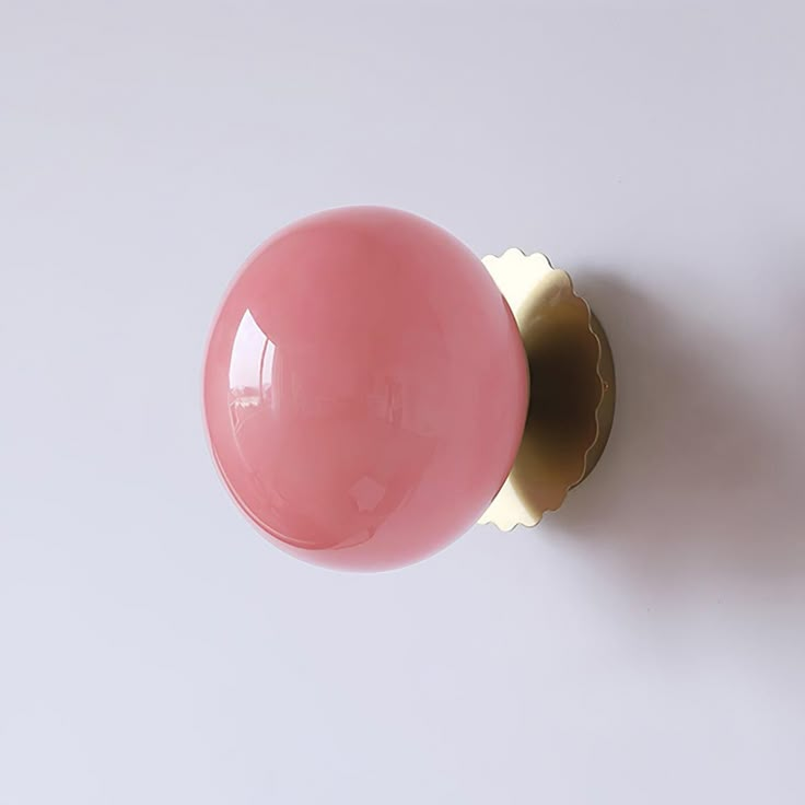 a pink door knob on a white wall