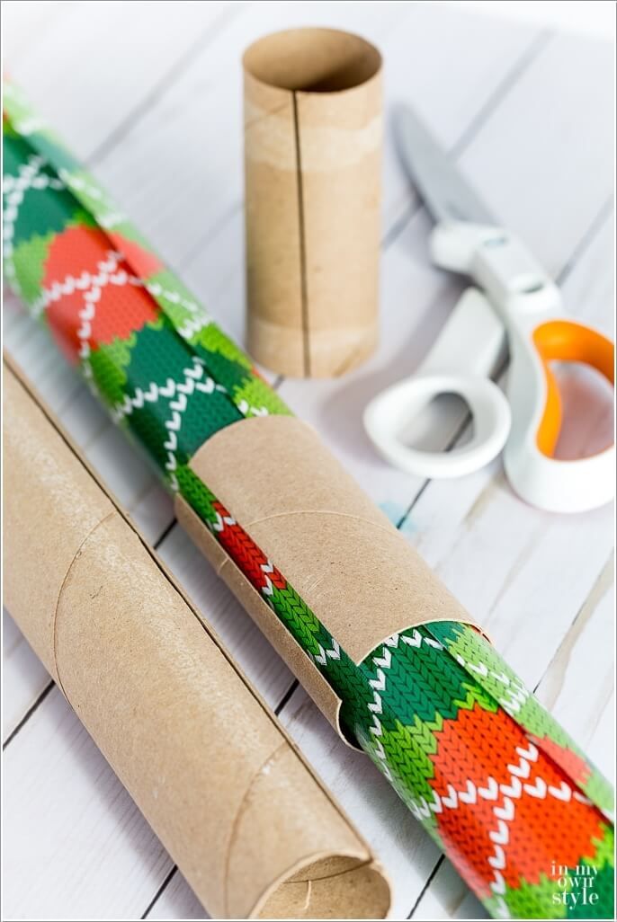 rolled up wrapping paper next to scissors and other crafting supplies on a white table