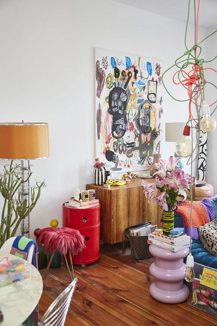 a living room filled with furniture and lots of colorful items on the floor next to a painting