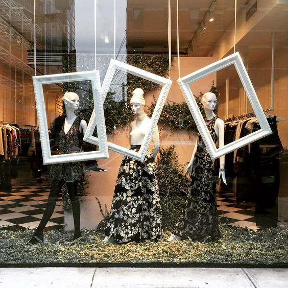 three mannequins dressed in black and white dresses are displayed behind glass windows