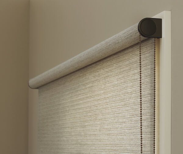 a close up of a closed roller shade in a room with beige walls and flooring