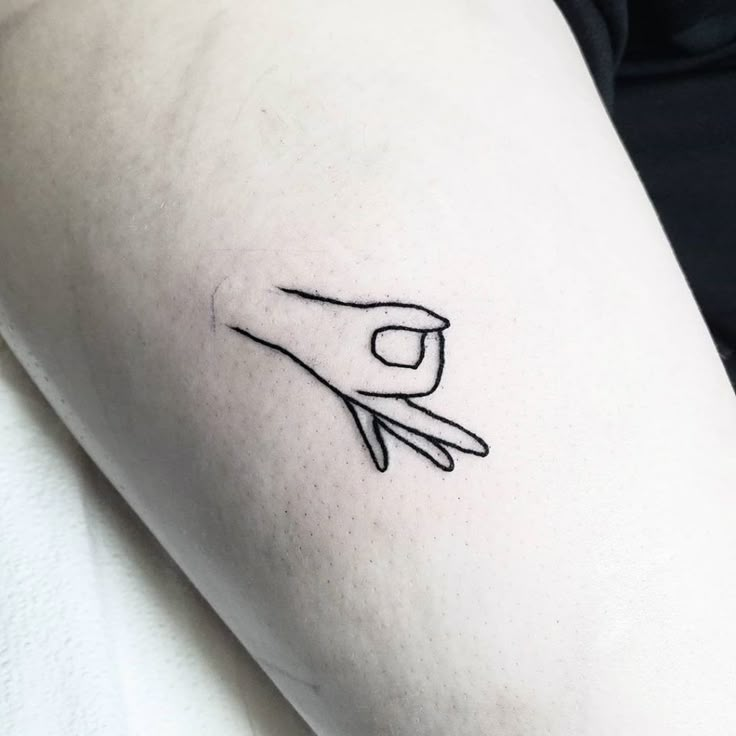 a small tattoo on the arm of a woman's left hand holding a tiny object