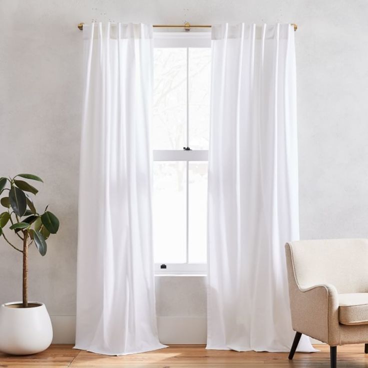 a white chair sitting next to a window in front of a potted plant on top of a hard wood floor