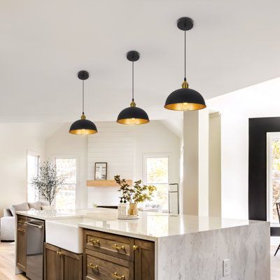 an open kitchen with marble counter tops and wooden cabinets, along with two pendant lights hanging from the ceiling